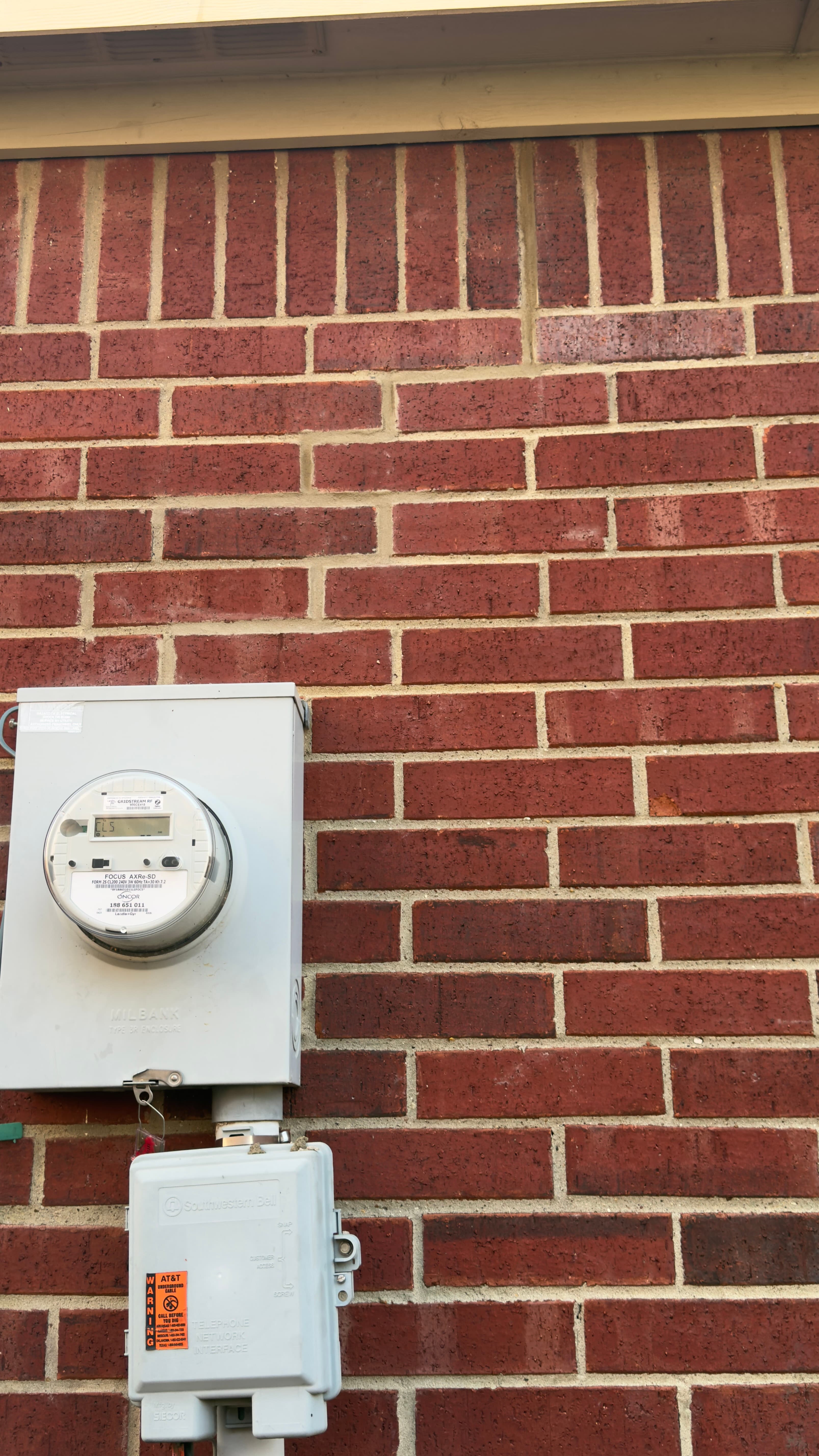 Hairline mortar cracks on a brick wall near utility meter