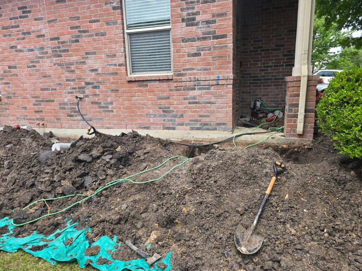 Pier installation trench dug along a Texas brick foundation